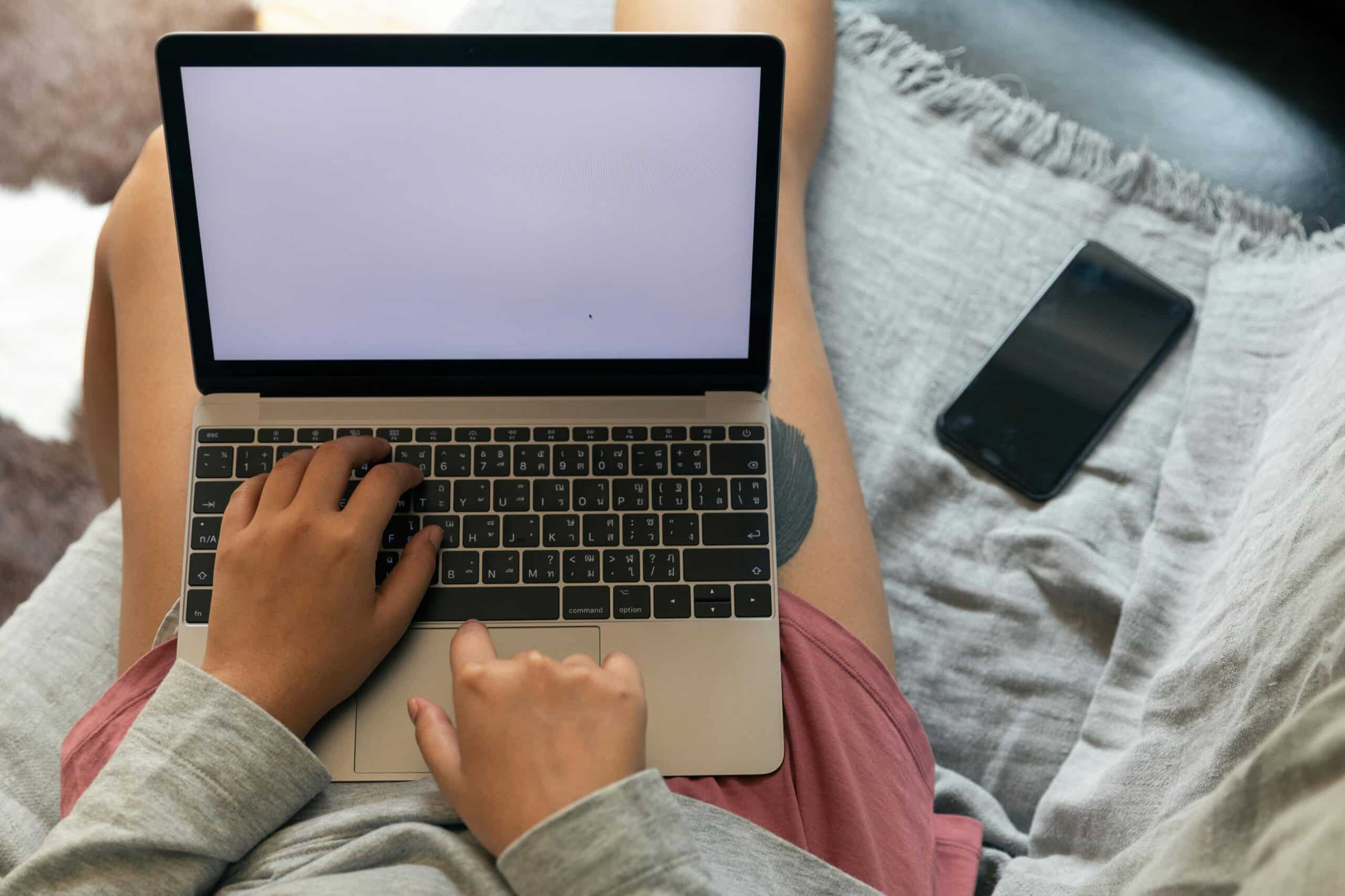 foto van iemand van bovenaf met laptop op schoot